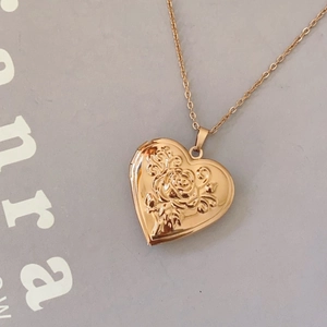 Close-up of rose gold heart locket necklace featuring embossed rose flower detail