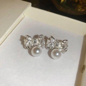 Détails macro de boucles d'oreilles nœud plissé argenté avec pendentifs perles