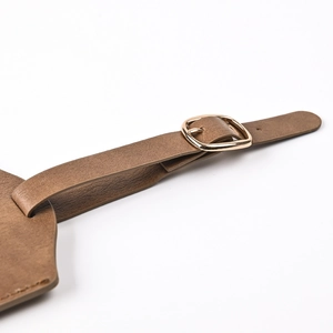 Close-up of brown PU leather luggage tag strap with high-quality metal buckle detail