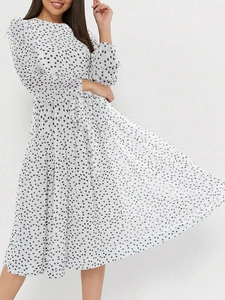 Détail de la robe mi-longue blanche à pois montrant la ceinture et la fluidité de l'ourlet