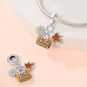 Detailed view of silver charm beads featuring sunflower, maple leaf and orange enamel handbag