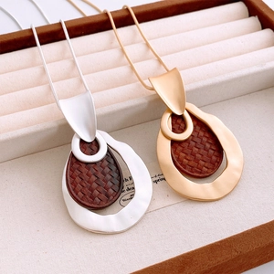 Detailed macro view of silver and gold geometric hollow pendants with dark wood texture