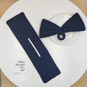 Flat lay detail of a navy blue bow hair bun maker tool on a clean white background