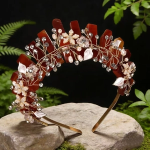 Detailed view of red gemstone floral crown with gold metal leaves on a mossy stone base