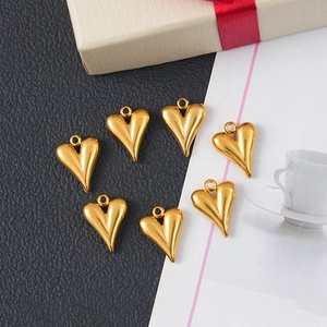 Polished gold stainless steel heart charms for DIY jewelry making on a textured background