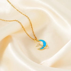 Detail of gold crescent moon and star pendant with blue enamel on beige silk