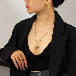 Professional model wearing golden sun pendant necklace with matching ring and stud earrings