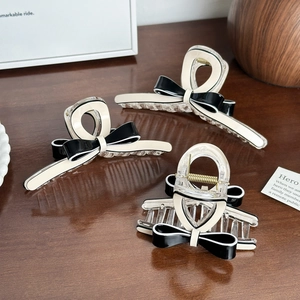 Elegant large black and white bow hair claw clips for women on a dark wooden table