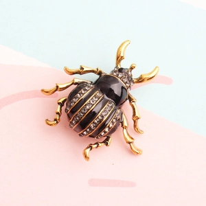 Elegant black enamel beetle brooch with gold-tone plating and sparkling rhinestones