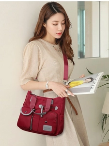 Large red oxford nylon shoulder bag with multi-pocket design shown on model style