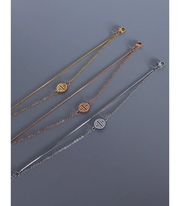 Detail of snake bone chain and round plate in gold, silver, and rose gold titanium steel
