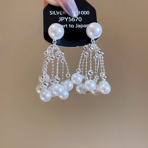 Detail of silver drop earrings with white pearls and long metal tassel chains