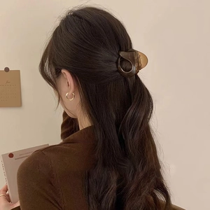 Detail of dark amber acrylic hair claw clip worn by a model with elegant styling