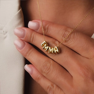 Detailed view of a personalized gold bubble letter necklace featuring the name Emma