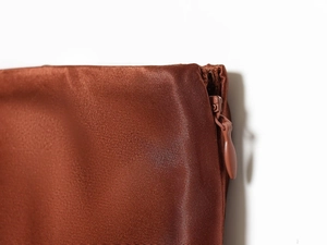 Detailed view of the smooth brown satin fabric and matching zipper of this midi skirt