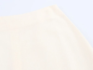Close-up of cream cotton-linen fabric texture on the waistband of a vacation skirt
