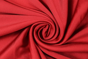 Macro shot of vibrant red knitted fabric texture with elegant spiral pleated detail