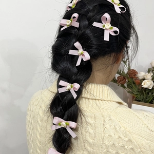Détail de barrettes à nœuds roses avec roses blanches sur une coiffure tressée