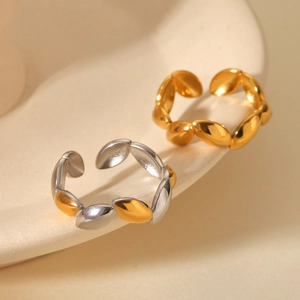Macro detail of leaf-shaped adjustable rings in gold and silver finish on ceramic