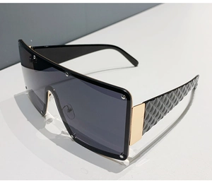 Detail of oversized black wrap sunglasses with gold metal hinges and quilted temples