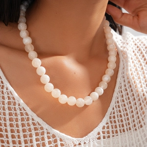 Close-up of translucent white round beads necklace worn on a model's neck