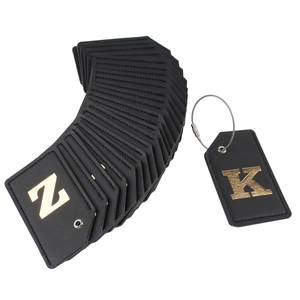 Close-up of black leather luggage tags with gold foil letters and steel cable loop