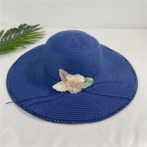 Detail of navy blue straw hat with lace edges and floral embroidery for sun protection