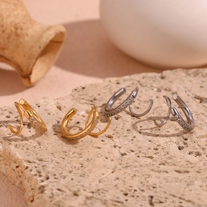 Détail macro de boucles d'oreilles spirales en or 18K et argent avec pavé de zircons