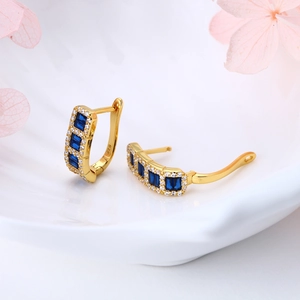 Macro shot of 925 sterling silver gold earrings with blue rectangular stones and crystals