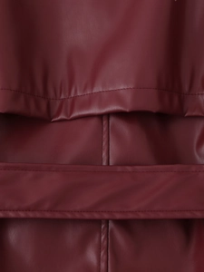 Vue macro détaillée de la texture du cuir PU bordeaux et des coutures à la taille du manteau