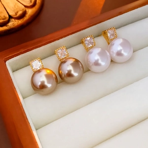 Gold plated pearl stud earrings with square cubic zirconia in a white jewelry box