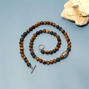 Detail of 8mm tiger eye and lava stone beads with silver toggle clasp on blue background