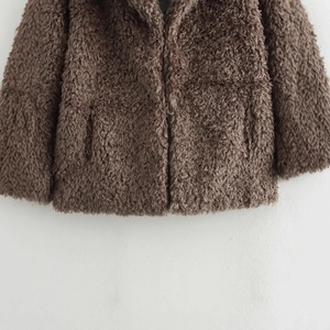 Brown teddy fur coat with plush texture and detailed cuffs on a white backdrop