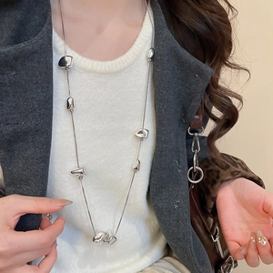 Detail shot of a silver irregular geometric beaded necklace layered on a sweater