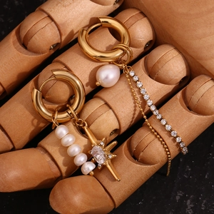 Detailed view of asymmetric gold star earrings with freshwater pearls and tassels