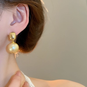 Gros plan sur les accents carrés plaqués or 18 carats et grandes perles champagne