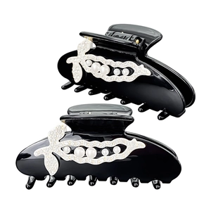 Detail view of elegant black resin hair claws with white pearls and sparkling rhinestones