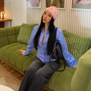 Dettaglio di camicia a righe blu abbinata a berretto in maglia rosa e borsa nera
