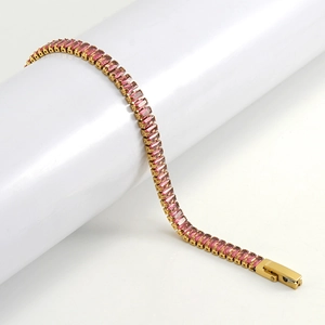 Macro view of gold tennis bracelet featuring rectangular pink zirconia stones on a white stand