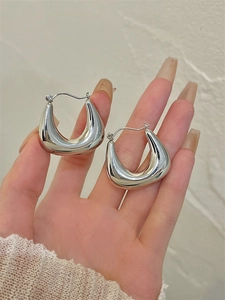 Gros plan de boucles d'oreilles épaisses en forme de U en argent poli miroir