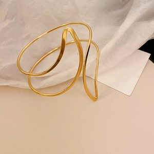 Détail du bracelet doré minimaliste avec des lignes ondulées élégantes et ajourées