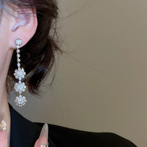 Close-up of elegant silver floral drop earrings with sparkling rhinestones on model