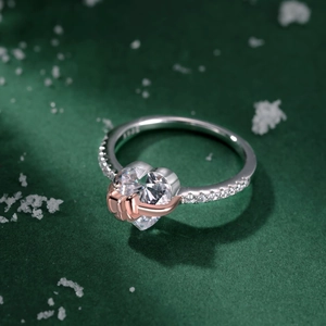 Macro detail of S925 silver ring featuring rose gold hands holding a heart zircon stone