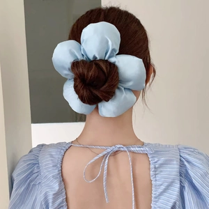 Blue satin flower hair tie elastic scrunchie shown on model's bun hairstyle