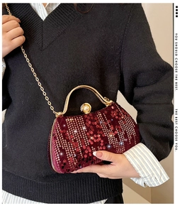 Close-up of wine red sequin evening clutch with gold metal handle and pearl clasp