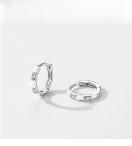 Detail of S925 sterling silver bamboo hoop earrings with white enamel and cubic zirconia