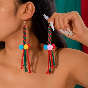 Close-up of colorful woven Christmas earrings with soft pom-poms on a female model