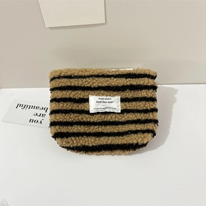Detail of plush striped brown pouch with white woven label and soft fleece texture