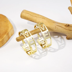 Detailed view of gold C-shaped hoop earrings with hollow LOVE letters on wood branch