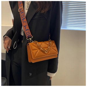 Detail of caramel quilted crossbody bag with a chunky chain and a wide striped strap